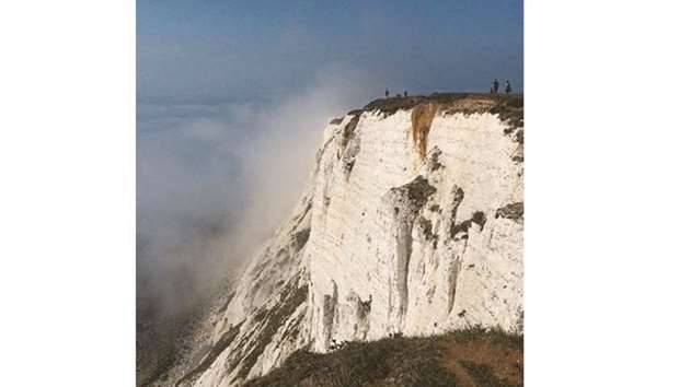In this image taken from social media, people are seen on a cliff at Beachy Head amidst mist, near Eastbourne.