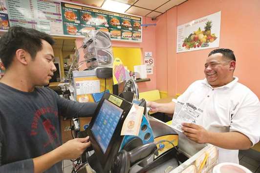 Martin Mendiola, right, a cook at Din Tai Fung, a Taiwanese restaurant located at the Americana at Brand shopping centre in Glendale, Calif., buys a lottery ticket from Don Chhun at Christina Donuts.