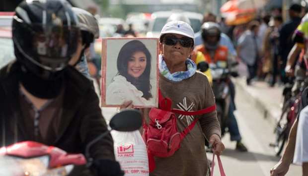 A supporter carries a photo of former Thai Premier Yinluck Shinawatra as they wait for her arrival at the Supreme Court in Bangkok on August 25, 2017