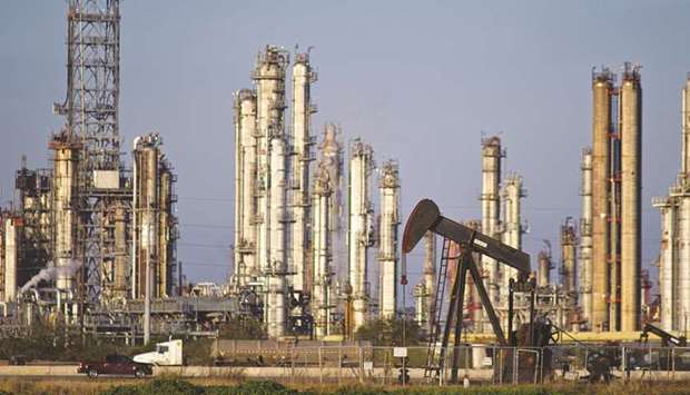 A refinery stands in the background as a pump jack operates in an oil field near Corpus Christi, Texas. Hedge funds lost faith in oil just before the worst storm to hit the US since 2004 struck the heart of energy production in Texas.