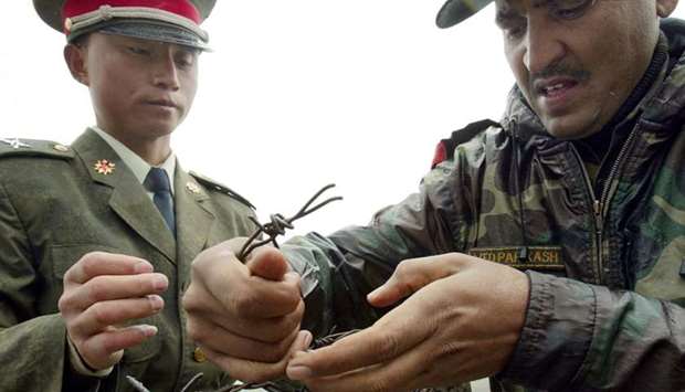 A Chinese soldier (L) and Indian soldier placing a barbed wire fence following a meeting of military representatives at the Nathu La border crossing between India and China in India's northeastern Sikkim state. File photo taken on July 5, 2006.