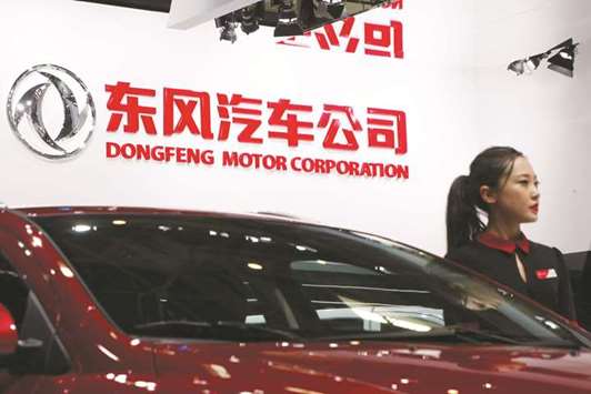 A hostess poses next to Dongfeng Motoru2019s A9 sedan at an auto show in Beijing. China, the worldu2019s biggest auto market, wants all-electric battery cars and plug-in hybrids to account for at least one-fifth of its vehicle sales by 2025, as policymakers grapple with alarming  pollution levels in major cities.
