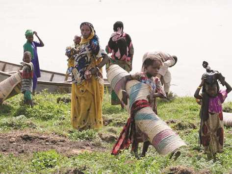Chadian women carry carpets and few other belongings as they travel back on Midikouta Island on Lake Chad.