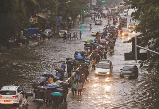 Commuters walk through water-logged roads after rains in Mumbai yesterday.