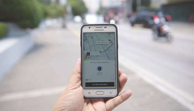 A man posing with his mobile phone displaying the Uber app in Manila.