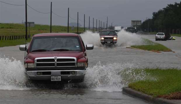 Vehicles drive along a flooded road in Houston