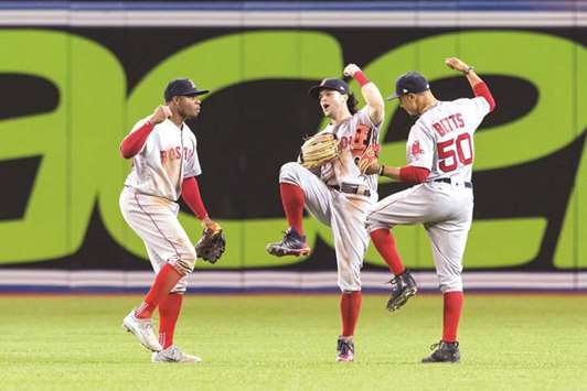 Boston Red Soxu2019s Rajai Davis (left) and Dustin Pedroia and Mookie Betts (right) celebrate their win over the Toronto Blue Jays at Rogers Centre in Toronto, Canada, on Tuesday. (USA TODAY Sports)