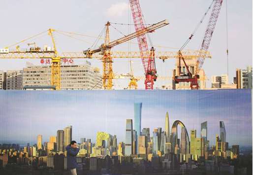 A man walks past the hoarding of a construction site in Beijing. Moodyu2019s Investors Service said surprisingly strong data in the first half of the year prompted it to raise 2017 growth forecasts for China to 6.8% from 6.6%.