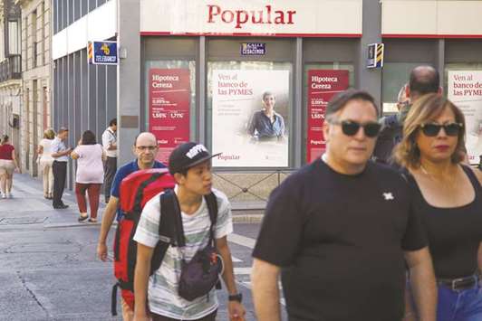 Pedestrians pass a Banco Popular Espanol branch in Madrid. Banco Popularu2019s shareholders and junior bondholders lost around u20ac4bn ($4.82bn) after an EU agency forced the sale of the lender, then the sixth largest in Spain, to bigger rival Santander for the nominal price of one euro.
