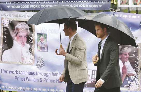 Prince William and Prince Harry look at tributes left yesterday by members of the public at one of the entrances of Kensington Palace to mark the 20th anniversary today of the death of Diana, Princess of Wales, in London.