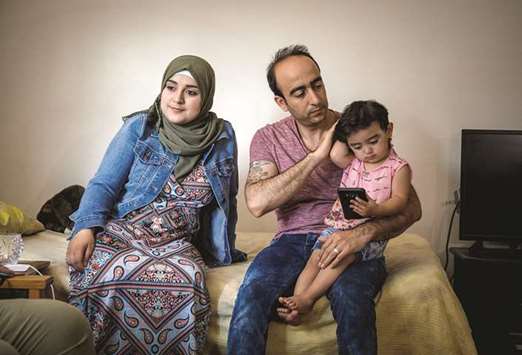 Baraa, Abdulmajeed and Sham Haj Khalaf sit in the living room of their Skokie, Ill. home. The family emigrated as refugees from Syria.