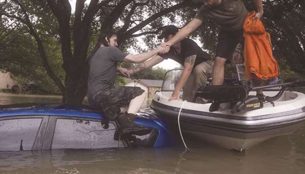 A Houston resident, hypothermic and shaking, is rescued from atop his car in the Bear Creek neighbourhood which flooded after water was released from nearby Addicks Reservoir.