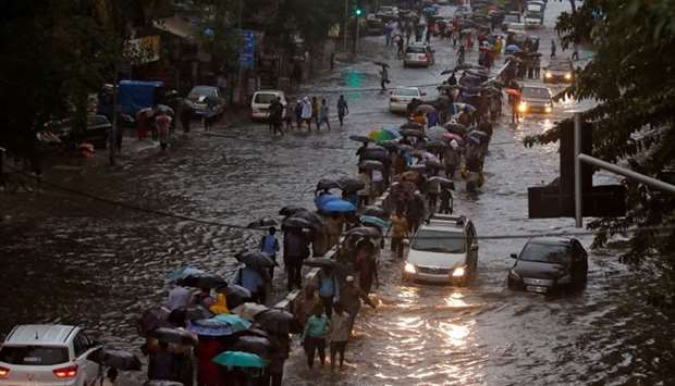 Commuters walk through water-logged roads after rains in Mumbai.