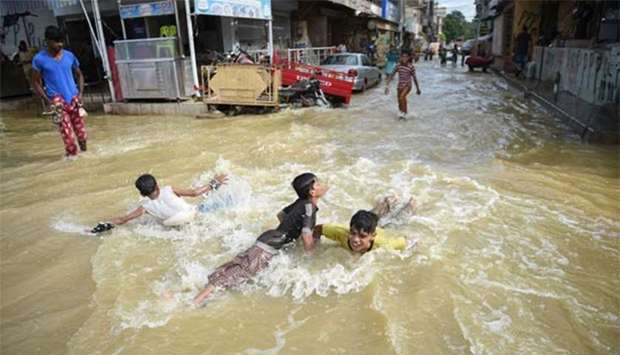 Pakistani children play in a flooded street after heavy rain in Karachi on Thursday.