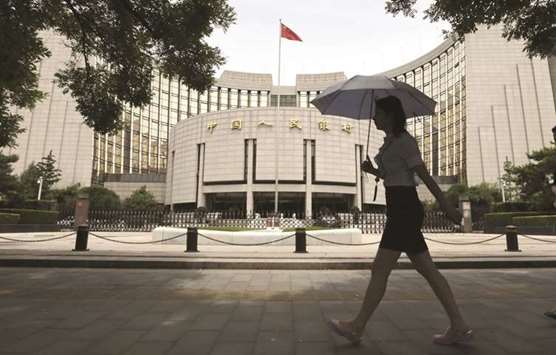 A pedestrian walks past the Peopleu2019s Bank of China building in Beijing. Institutions will not be allowed to issue negotiable certificates of deposit (NCD), a popular short-term debt instrument for smaller banks in the interbank market, with a tenor exceeding one year from today, the central bank said yesterday.