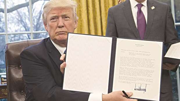 File photo of President Donald Trump holding up an executive order withdrawing the US from the Trans-Pacific Partnership on January 23.