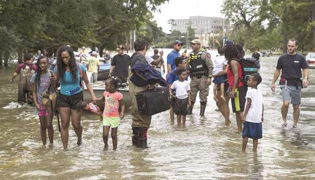 Families walk out of the water in Houston. Residents were rescued from their flooded homes and apartments due to high water coming from the Addicks Reservoir after Hurricane Harvey.