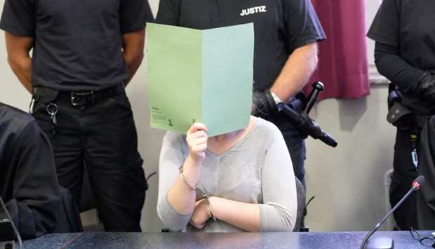 The defendant Xenia I covers her face with a folder during a verdict reading in a courtroom of the regional court in Dessau Rosslau, Germany
