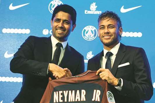 Brazilian superstar Neymar (R) shakes hands with Paris Saint Germainu2019s Qatari president Nasser al-Khelaifi during a press conference at the Parc des Princes stadium in Paris.