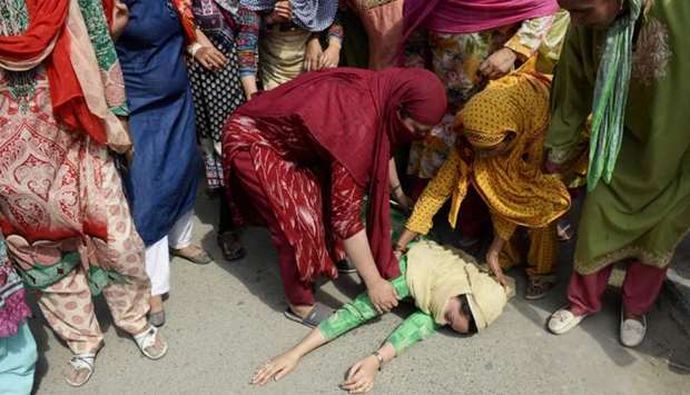 A Kashmiri woman lies on the ground after fainting fainted during the funeral procession of slain militant Yawar Nissar at Shipora in Anantnag, South of Srinagar, on August 4