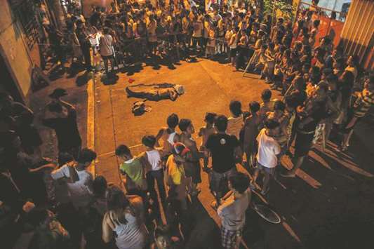 Residents flocking around the dead body of an alleged drug user killed by unidentified assailants in Manila. The Philippines said it would tell visiting US Secretary of State Rex Tillerson his concerns over its drug war that has claimed thousands of lives were due to u201cexaggerated media reportsu201d.