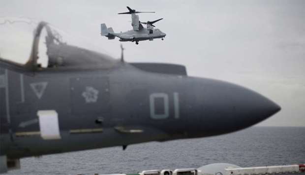 US Marines MV-22 Osprey Aircraft flies over a jet before landing on the deck