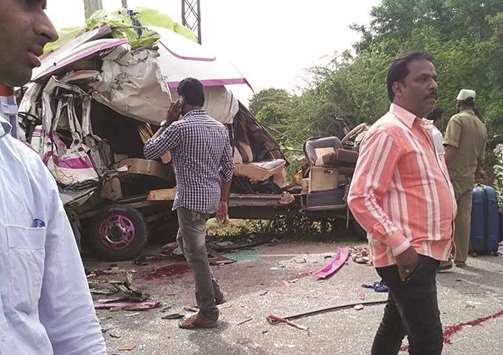People stand next to the wreckage of a minibus, in which a group of Spanish tourists were travelling, after it collided with a container truck in Punganur, in Andhra Pradesh yesterday.