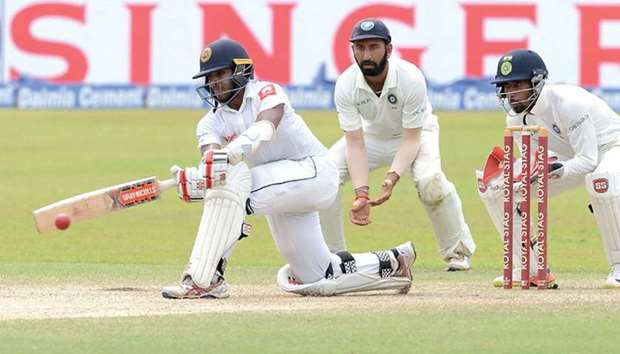Sri Lankau2019s Kusal Mendis (left) plays a shot as Indian wicketkeeper Wriddhiman Saha (right) and Cheteshwar Pujara (centre) look on on third day of the second Test at the Sinhalese Sports Club (SSC) Ground in Colombo yesterday. (AFP)