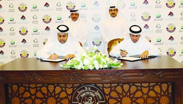 Al-Khanji and al-Abdulla sign the MoU between Mwani Qatar and Muntajat in the presence of HE al-Sulaiti and al-Kaabi