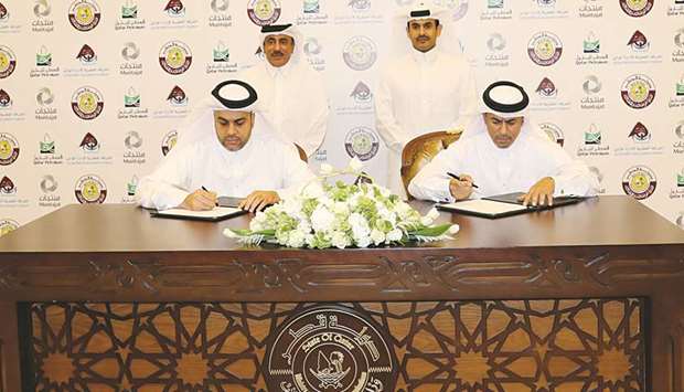 Al-Khanji and al-Abdulla sign the MoU between Mwani Qatar and Muntajat in the presence of HE al-Sulaiti and al-Kaabi.