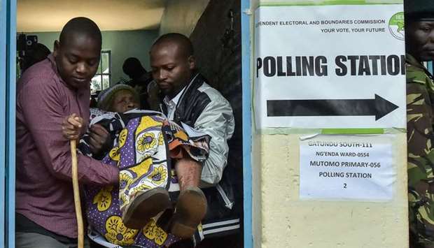Kenya's Withira Wainana 81-years-old, is assisted after voting at the polling station in the general elections on August 8, 2017, in Gatundu, Kiambu county