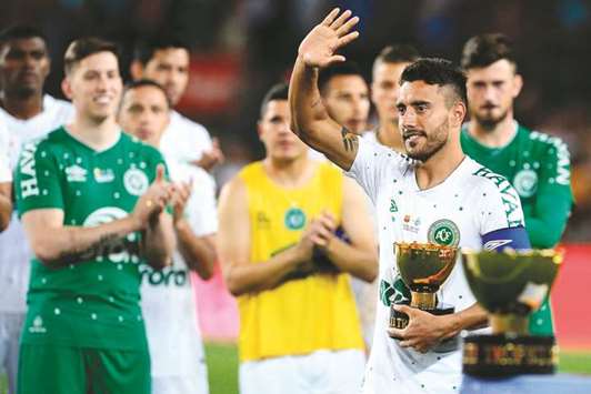 Chapecoenseu2019s defender Alan Ruschel waves to Barcelona players as he holds the second place trophy.