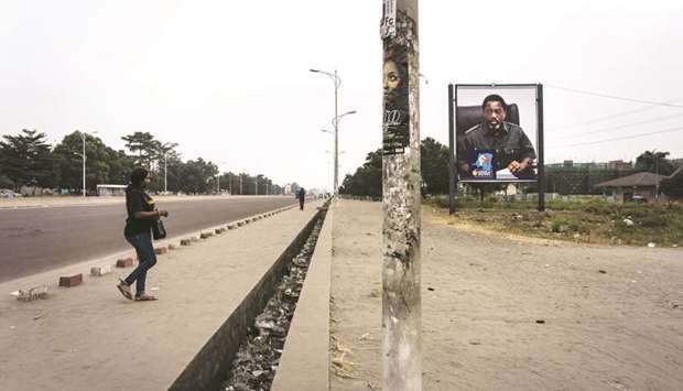 A woman crosses an empty boulevard in Kinshasa sporting a placard of President Kabila during the u2018dead cityu2019 action.