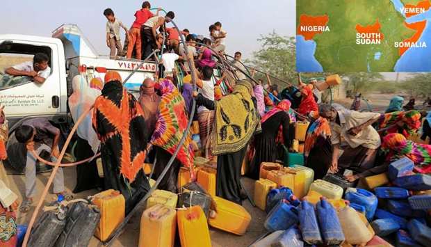 People gather around a charity tanker truck to fill up their jerrycans with drinking water in Yemen