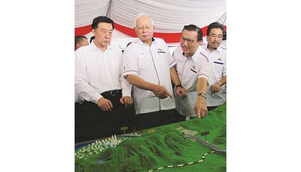 Malaysiau2019s Prime Minister Najib Razak and Transport Minister Liow Tiong Lai (2nd from right) look at a model of the East Coast Rail Line at Kuantan Bahang, Malaysia yesterday. The planned 688km East Coast Rail Link will connect the South China Sea, large parts of which are claimed by China, at the Thai border in the east with the strategic shipping routes of the Straits of Malacca in the west.