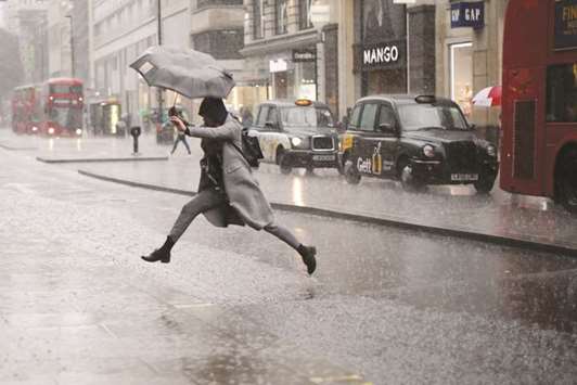 A pedestrian leaps over a puddle as rain fell in central London yesterday.