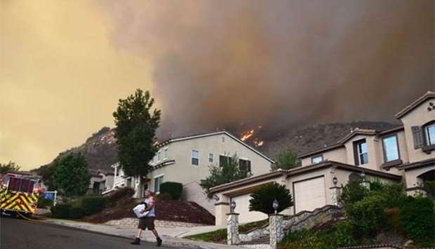 A man removes belongings from his home as flames of the Holy Fire approach in Lake Elsinore, California, southeast of Los Angeles, on Thursday.
