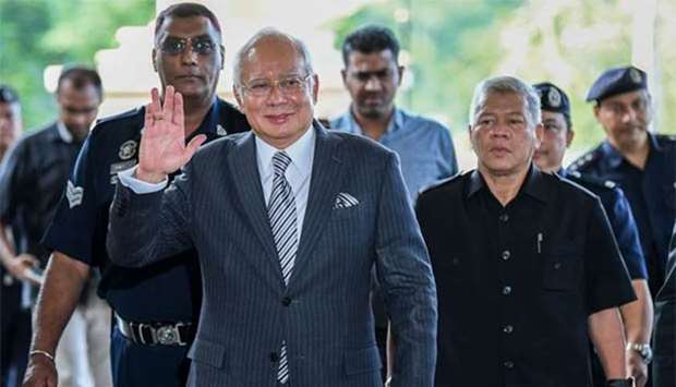 Malaysia's former prime minister Najib Razak waves as he arrives for a court appearance at the Duta court complex in Kuala Lumpur on Friday.