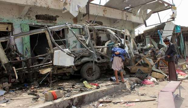 Yemenis gather next to the destroyed bus at the site of a Saudi-led coalition air strike, that targeted the Dahyan market.