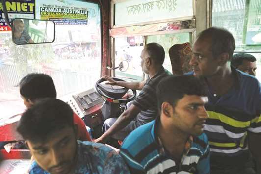 Passengers sit close to the driver as they ride in a bus in Dhaka.