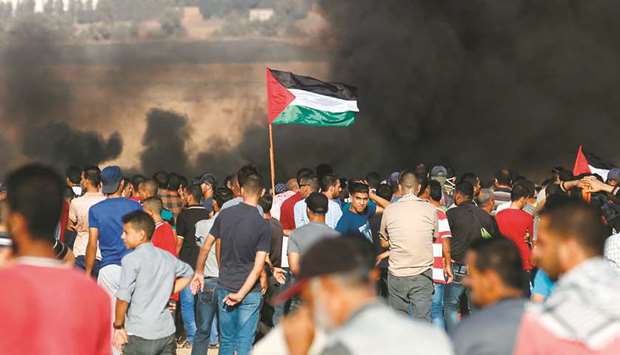 Palestinian protesters wave their national flag as they gather during a demonstration at the Israel-Gaza border, in Khan Yunis in the southern Gaza Strip, yesterday.