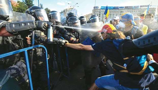 Police scuffle with protesters using teargas during an anti-government protest in front of the Romanian government headquarters in Bucharest.
