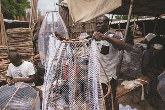 A man covers a wooden frame with fishing net to construct a fish trap in Baga fish market in Maiduguri.
