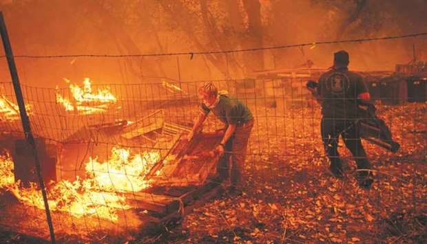 Fifteen-year-old Alex Schenck moves flaming pallets while fighting to save his home as the Ranch Fire tears down New Long Valley Rd near Clearlake Oaks, California.