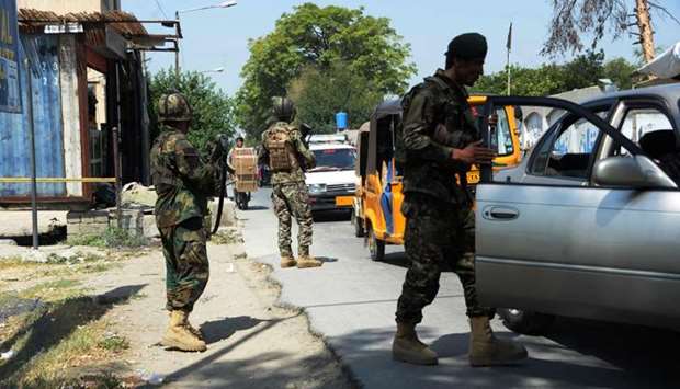 Afghan National Army (ANA) soldiers search vehicles at a checkpoint in the city of Jalalabad