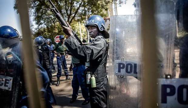 Zimbabwean anti-riot police officers stand guard and close the gate of the Rainbow Towers where the election's results were announced, as supporters of the opposition party Movement for Democratic Change (MDC), protest against alleged widespread fraud by the election authority and ruling party, in Harare, on August 1, 2018.