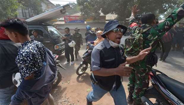 An Indonesian soldier (R) and an official (C) try to calm people shortly after an aftershock hits the area in Tanjung on Lombok island