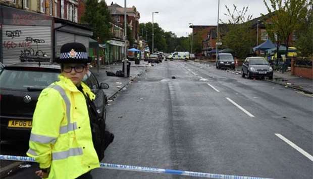 Police officers stand guard at the scene of a shooting at Claremont Road in the Moss Side neighbourhood of Manchester on Sunday.