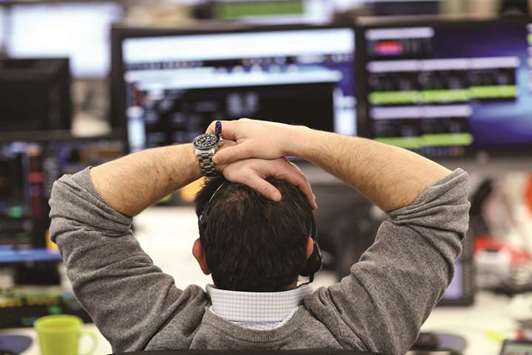 A broker looks at financial information on computer screens on the IG Index trading floor in London (file). The FTSE 100 fell 1.2% to close at 7,652.91 points yesterday.