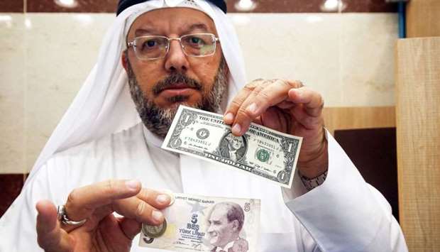 A Kuwaiti man holds a one US dollar bill next to a five Turkish lira banknote at a currency exchange in Kuwait City.